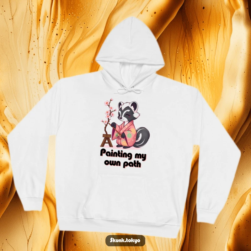 Funny and warm hoodie featuring a skunk in a vibrant kimono, painting cherry blossoms, perfect for cozy creative moments.