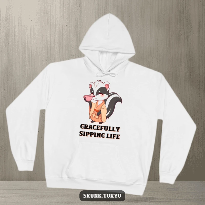 Funny and warm hoodie featuring a skunk in a kimono gracefully balancing a tea cup, perfect for cozy, humorous relaxation.