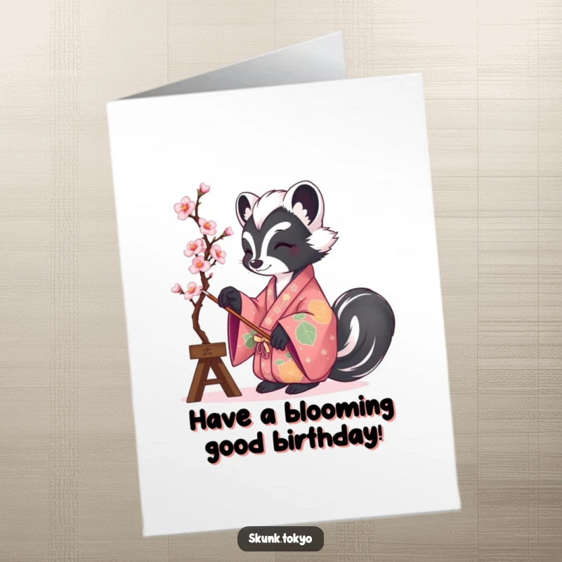 Funny Free Printable Birthday Card: A skunk in a colorful kimono meticulously painting a beautiful cherry blossom branch with focus.
